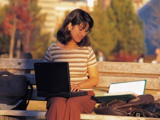 student sitting on a park bench studing